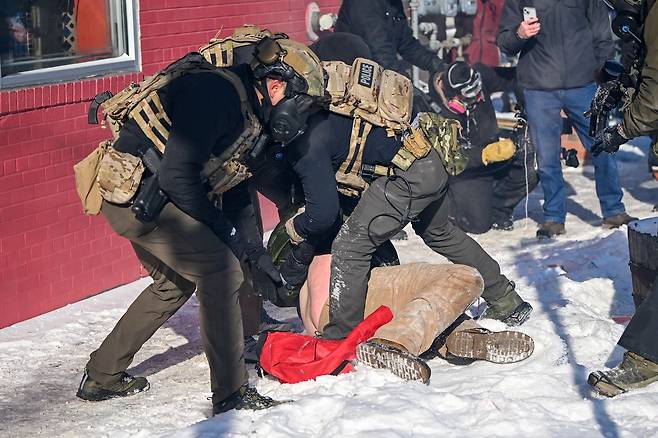 현지시간 24일 미국 미네소타주 미니애폴리스에서 치명적 총격 사건 이후 발생한 대치 상황에서 연방 요원이 시위자를 체포하고 있다. EPA=연합뉴스