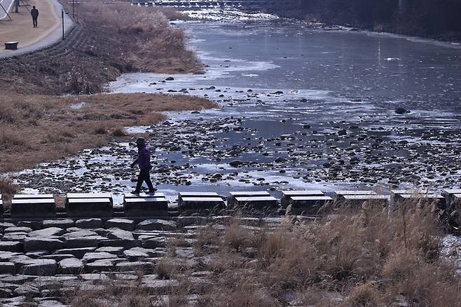 ▲ 22일 연일 강추위가 이어지는 가운데 대구 수성구 용두교 일대 신천에서 시민이 얼어붙은 수면 옆 돌다리를 건너고 있다. 권남인 기자 kni@kyougbuk.com