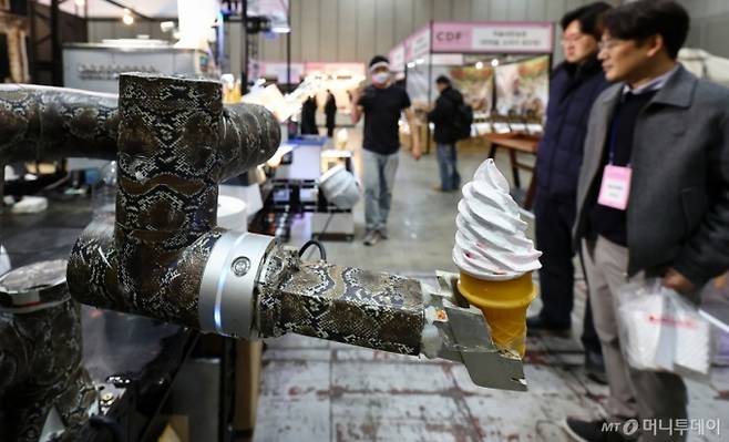 (고양=뉴스1) 김도우 기자 = 22일 경기 고양시 킨텍스에서 열린 2026 카페디저트페어에서 관람객들이 로봇이 전달하는 아이스크림을 지켜보고 있다. 2026.1.22/뉴스1 Copyright (C) 뉴스1. All rights reserved. 무단 전재 및 재배포, AI학습 이용 금지. /사진=(고양=뉴스1) 김도우 기자