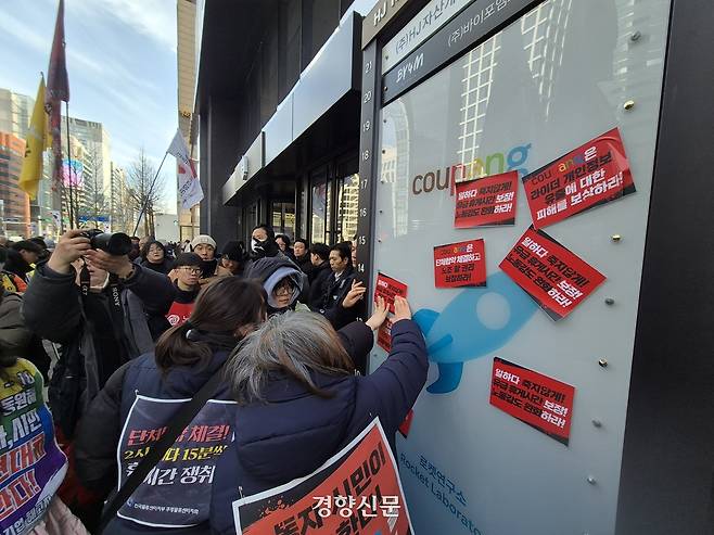 ‘1·30 쿠팡 규탄 분노의 시민대행진’ 참가자들이 30일 서울 강남구 쿠팡로지스틱스(CLS) 본사 앞에서 집회를 열고 항의 구호가 적힌 스티커를 사무실 앞에 붙이고 있다. 김태욱 기자