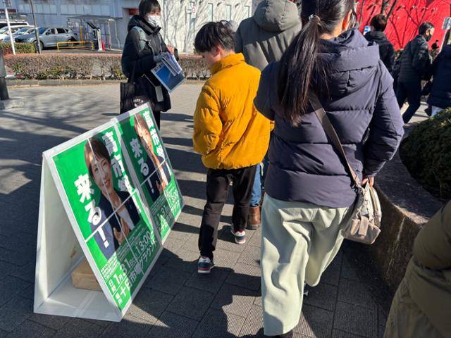 한 아이가 지난달 31일 일본 가나가와현 요코하마시 미도리구에 설치된 다카이치 사나에 총리 집권 자민당 중의원 선거(총선) 후보 지원 유세 안내판을 보고 있다. 요코하마=류호 특파원