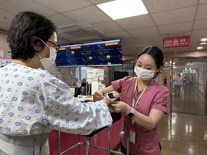 CM병원 간호사가 환자에게 스마트 병상 모니터링 시스템 '씽크'와 연동되는 웨어러블 기기를 착용시키고 있다.(사진=대웅제약)