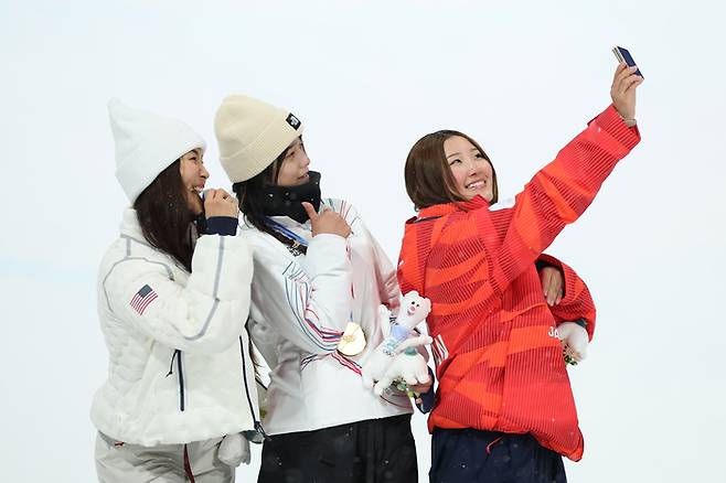 최가온(가운데)이 13일(한국시간) 이탈리아 리비뇨에서 열린 2026 밀라노-코르티나 동계올림픽 스노보드 여자 하프파이프에서 금메달을 따낸 뒤 ‘우상’ 클로이 김(왼쪽), 동메달을 따낸 미츠키 오노와 ‘빅토리 셀피’를 찍고 있다. 사진 | 게이티미지·삼성전자