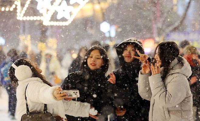 서울 마포구 홍대 인근에 눈이 내리는 가운데 외국인 관광객들이 기념촬영을 하고 있다. 연합뉴스