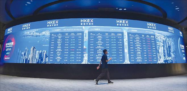 2025년 5월 20일 홍콩증권거래소에서 한 남성이 전광판 앞을 지나가고 있다. (Xinhua=연합뉴스)