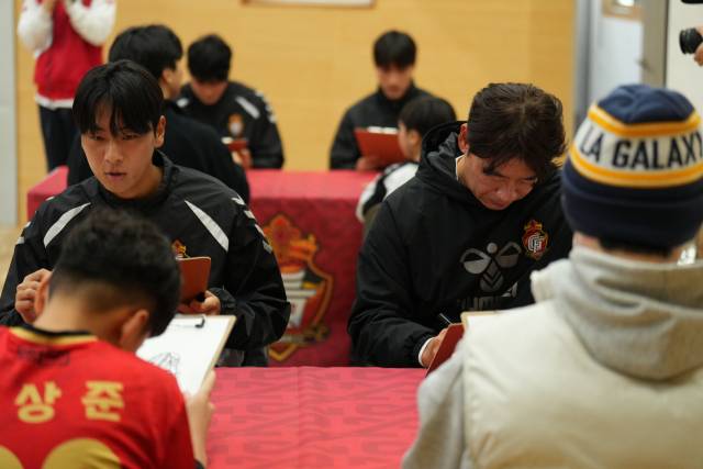 경남FC 팬미팅 행사에서 선수단과 참석자들이 하이파이브를 하고 있다. 오른쪽 사진은 선수단과 참석자들이 서로 캐리커처를 그려주고 있는 모습./경남FC/