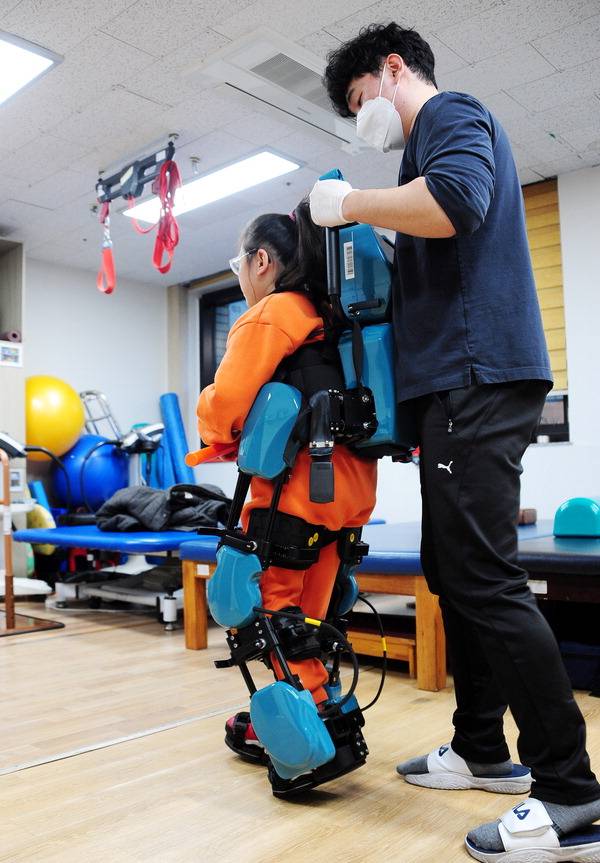 지난 10일 부산 연제구 부산장애인종합복지관 2층 재활치료실에서 이재서 작업치료사가 김유리 양과 로봇을 이용한 보행 치료를 하고 있다. 김성효 선임기자