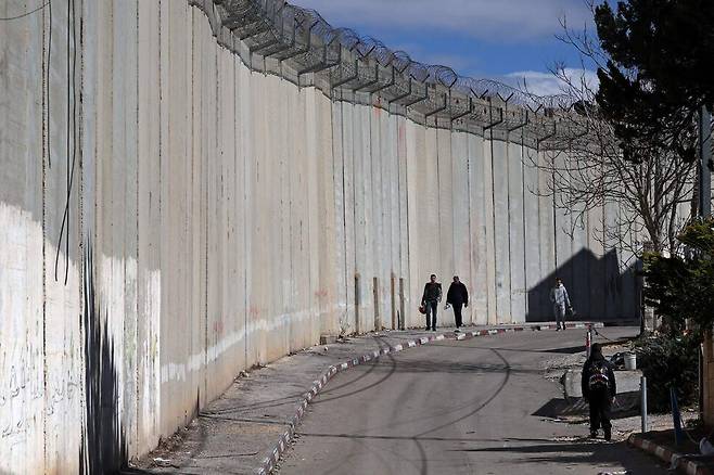 24일(현지시각) 이스라엘에 점령된 요르단강 서안지구 동예루살렘 인근 다히아드 바리드에 세워진 분리 장벽 주변을 팔레스타인 주민들이 걷고 있다. AFP 연합뉴스