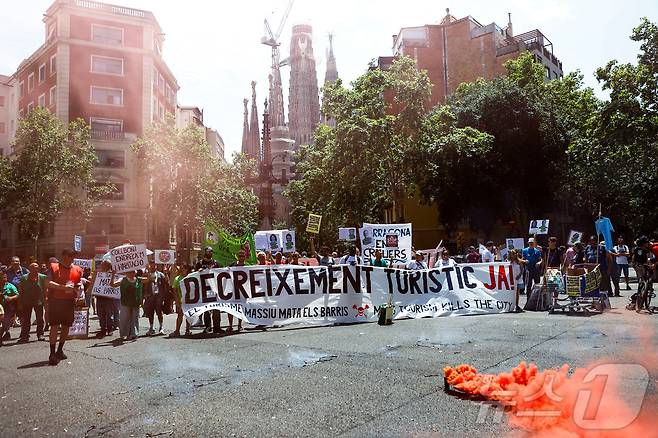 지난해 6월 15일 스페인 바르셀로나에서 사람들이 대규모 관광에 반대하는 시위에 참여해 현수막을 들고 있다. 2025.06.15. ⓒ 로이터=뉴스1