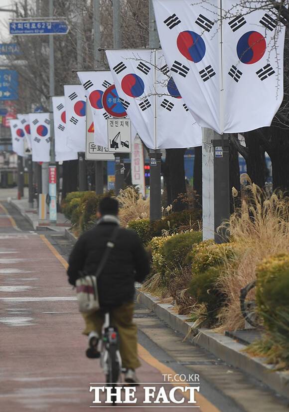 6일 오전 서울 영등포구 국회대로에 걸린 태극기 옆으로 한 시민이 자전거를 타고 지나가고 있다.