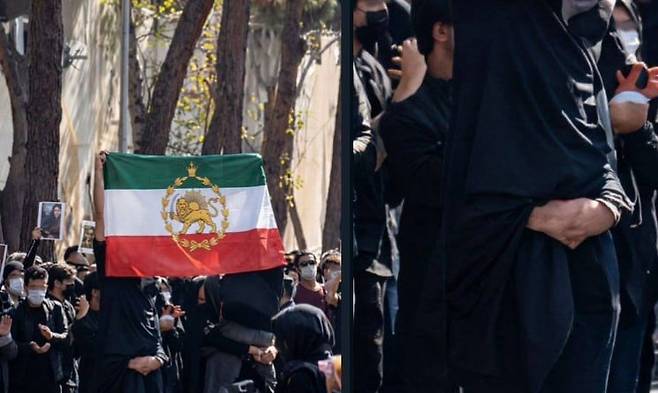 이란 내 히잡을 쓴 반정부 시위, 옛 사자가 그려진 옛 팔레비 왕조 이란 깃발을 든 맨앞 시위대 참가자 손을 확대해 보면 뭉개져 있다.(오른쪽)/X