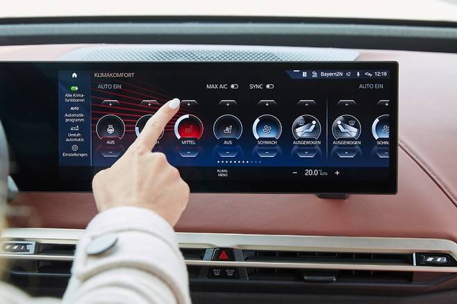 BMW iX 차량 인테리어, 운전자가 열선 시트를 작동하고 있다. 사진=BMW
