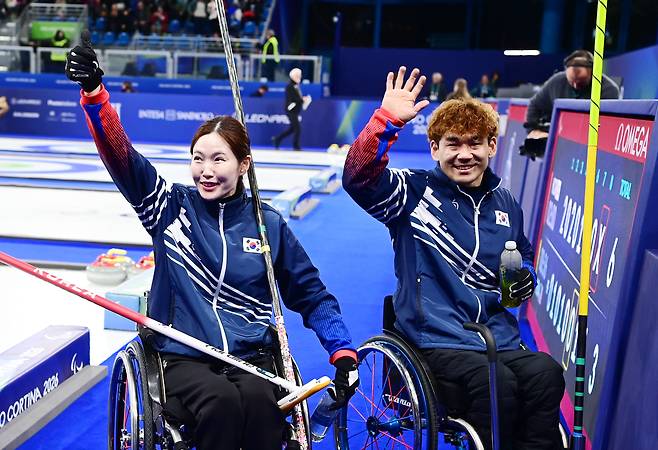 휠체어컬링 믹스더블 한국 백혜진, 이용석이 11일 2026 밀라노·코르티나담페초 동계 패럴림픽 결승 진출을 확정한 뒤 환호하는 응원단을 향해 손을 흔들며 인사하고 있다. 코르티나 | 공동 취재단