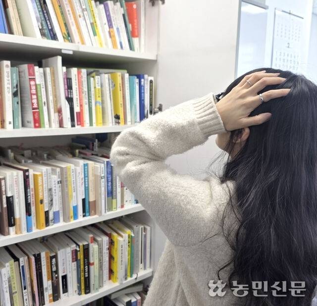 가득 찬 책장 앞에서 정리 방법을 고민하는 기자.