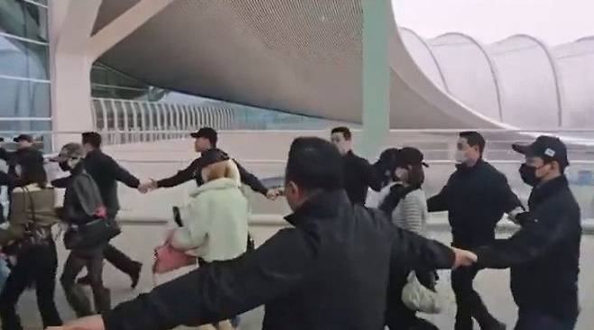 아이돌 그룹 하츠투하츠의 공항 이동 과정에서 이른바 '강강술래식' 경호 방식이 포착되며 과잉 경호 논란이 일고 있다. SNS 갈무리