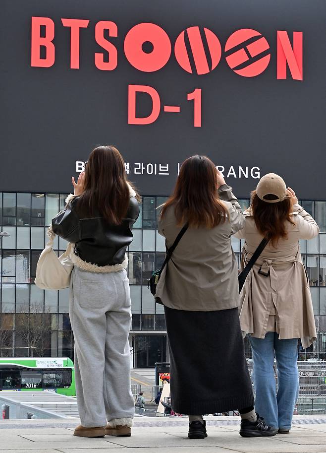 그룹 방탄소년단(BTS)의 컴백 공연을 하루 앞둔 20일 오전 서울 종로구 광화문광장에서 외국인 관광객들이 공연 광고를 스마트폰으로 촬영하고 있다. 임세준 기자