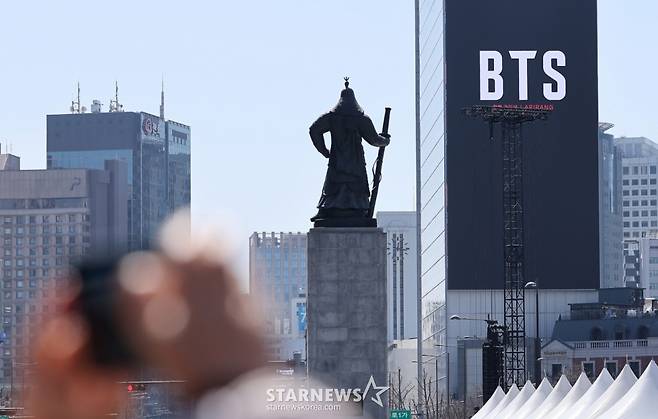 (서울=뉴스1) 김성진 기자 = 방탄소년단(BTS)의 서울 광화문광장 컴백 공연이 이틀 앞으로 다가온 19일 서울 종로구 광화문광장에서 시민들이 한 건물 외벽에 부착된 BTS 컴백 공연 광고물을 스마트폰으로 촬영하고 있다. 2026.3.19/뉴스1 Copyright (C) 뉴스1. All rights reserved. 무단 전재 및 재배포, AI학습 이용 금지. /사진=(서울=뉴스1) 김성진 기자