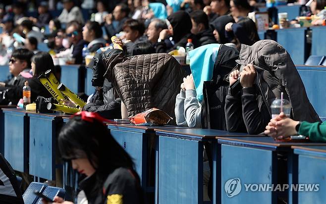 프로야구 시범경기 관람 (창원=연합뉴스) 김동민 기자 = 17일 경남 창원NC파크에서 열린 KIA 타이거즈와 NC 다이노스의 시범경기. 야구팬들이 겉옷으로 햇볕을 가린 채 응원하고 있다. 2026.3.17 image@yna.co.kr