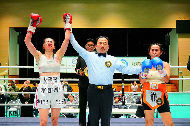 순천향대학교 부속 천안병원 소아청소년과 의사 서려경이 2026년 3월 충청남도 계룡시민체육관에서 세계복싱협회 미니멈급 아시아 챔피언결정전 주심 장관호로부터 승리 선언을 듣자 감격하고 있다. 국제여자복싱협회 아톰급 챔피언 노르즈 구로는 패배를 인정했다. 사진=KBM