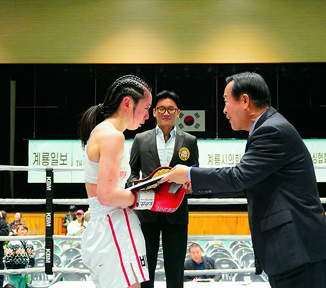 순천향대학교 부속 천안병원 소아청소년과 의사 서려경이 2026년 3월 충청남도 계룡시민체육관에서 세계복싱협회 여자미니멈급 아시아 챔피언 인정서를 받고 있다. 가운데는 김원석 WBA 아시아 사무총장. 사진=KBM