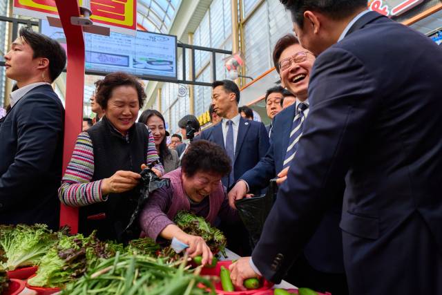 이재명 대통령이 25일 한국항공우주산업(KAI)에서 열린 KF-21 양산 1호기 출고식에 참석한 뒤 경남 진주시 진주중앙시장을 방문해 상인과 대화를 나누고 있다. 연합뉴스