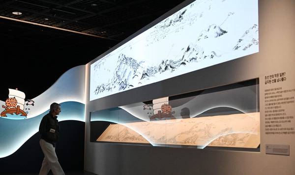 지난 24일 부산박물관 기획전시실에서 관람객이 ‘바다를 건너간 녀석들’에 나온 ‘초량화관도’를 보고 있다. 전시 공간 벽면에 부착된 부산박물관 캐릭터 흥구와 매기가 관람객을 맞이한다. 김성효 선임기자 kimsh@kookje.co.kr