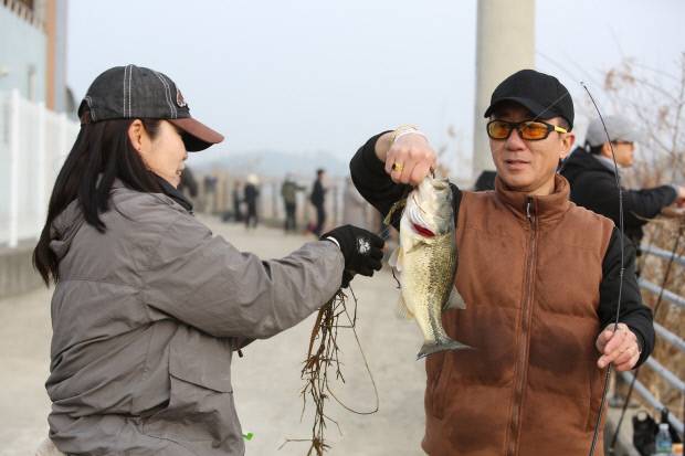 참가자들이 잡은 물고기의 낚싯바늘을 빼고 있다.