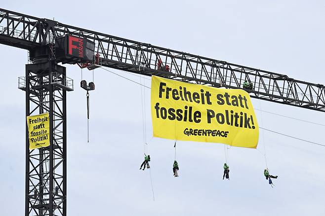 ▲지난 25일 독일 베를린 총리관저 위 건설 크레인에서 그린피스 활동가들이 “화석 연료 정책 대신 자유"라고 적힌 배너를 펼치고 있다. (사진=로이터/연합뉴스)