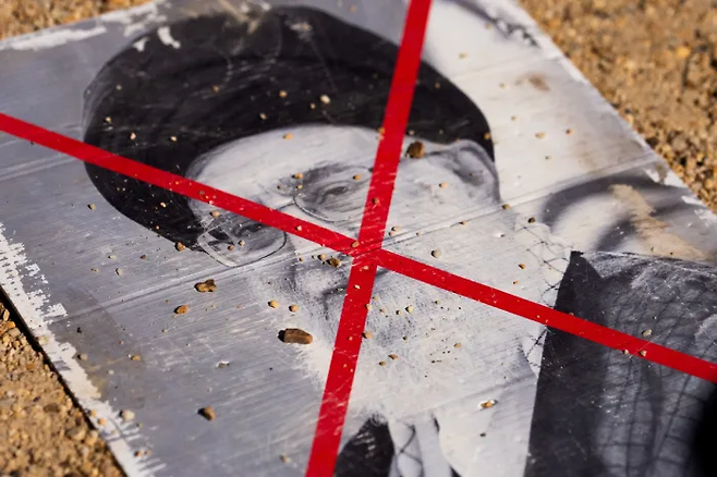 지난 29일 미국 워싱턴의 내셔널몰에서 열린 시위 중 미국과 이스라엘에 의해 사살된 아야톨라 알리 하메네이 이란 최고지도자의 사진에 줄이 그어져 바닥에 놓여 있다. 로이터연합뉴스