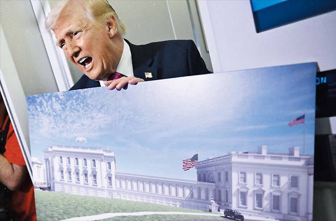 도널드 트럼프 미국 대통령이 지난달 29일 플로리다주에서 백악관으로 돌아오는 전용기 안에서 취재진에게 백악관 이스트윙을 철거하고 연회장을 건설하는 내용의 증축 조감도를 들어 보이고 있다. /AFP 연합뉴스