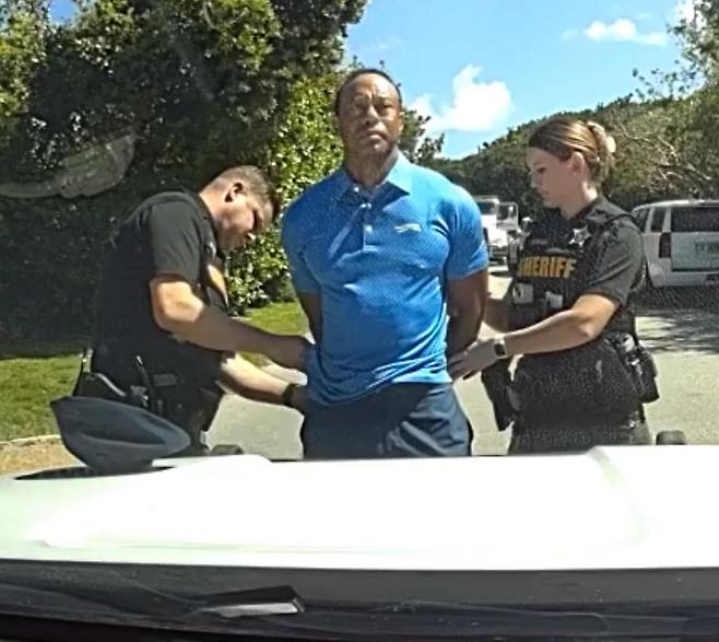 타이거 우즈(가운데)가 지난달 28일 미국 플로리다주 마틴카운티에서 심신미약 상태로 차를 몰다 사고를 낸 뒤 경찰에게 체포되고 있다. 사진 출처 마틴카운티 보안관 사무소