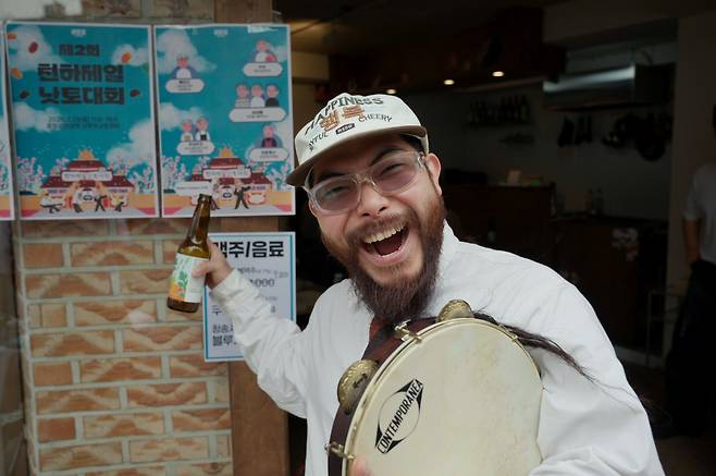 Kim Han, a percussionist and special guest performer, points to his illustrated self on the official event poster. (Tammy Park/The Korea Herald)