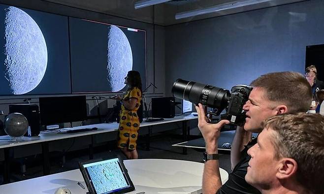 아르테미스 2호의 우주비행사 제레미 핸슨(카메라를 든 사람)과 임무 사령관 리드 와이즈먼이 휴스턴에 있는 존슨우주센터에서 달 사진 촬영 연습을 하고 있는 모습. 미국항공우주국 제공