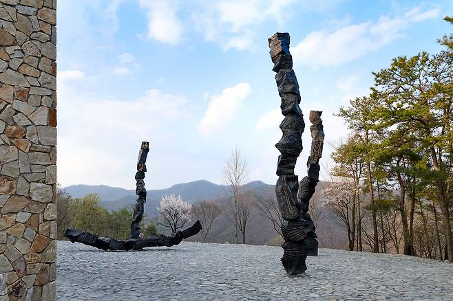 이배는 원주 뮤지엄 산 정원 ‘무(無)의 공간’에 높이 11m 브론즈 조각 ‘붓질’ 6점을 세웠다. 미술관 건물 높이만큼 숯을 탑처럼 쌓아올린 모습이다. 사진 뮤지엄 산