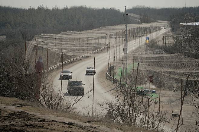 러시아-우크라이나 전쟁 중인 지난달 10일(현지시간) 하르키우주 이지움에서 드론 공격을 막기 위해 방어용 그물이 설치된 도로를 민간 차량과 군용 차량이 지나가고 있다. AFP=연합뉴스