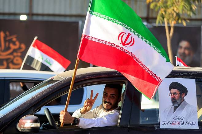 8일(현지시간) 이라크 바그다드 타흐리르 광장에서 미국과 이란의 휴전을 환영하는 행사에서 한 운전자가 이란 국기를 흔들며 손으로 V자를 그리고 있다./AFPBBNews=뉴스1