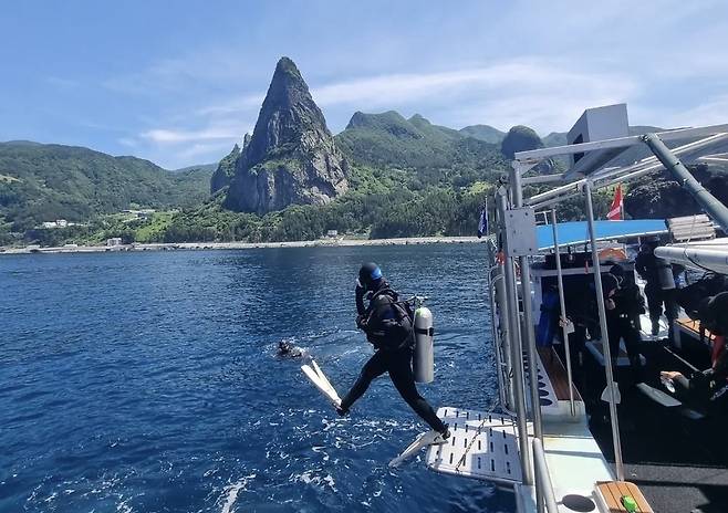 웅장한 송곳산을 배경으로 스킨스쿠버 다이버가 물속으로 뛰어들고 있다. 최근 젊은 층을 중심으로 울릉도를 정복하고 싶은 ‘완벽한 놀이터’로 인식하는 경향이 뚜렷해지면서, 민간 자구책을 넘어선 지자체의 정책적 해양 레저 인프라 확충이 시급해 보인다. /황진영 기자