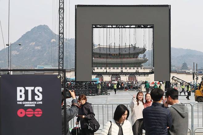 방탄소년단(BTS) 공연 종료 다음 날인 3월22일 서울 종로구 광화문광장에서 BTS 팬들이 철수 중인 무대를 배경으로 기념촬영을하고 있다. ⓒ연합뉴스