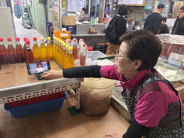 정치에 쏠린 눈 : 12일 부산 북구 구포시장에서 기름집을 운영하는 이모(73) 씨가 북갑 보궐선거 출마가 유력한 한동훈 전 국민의힘 대표의 영상을 시청하고 있다. 이시영 기자