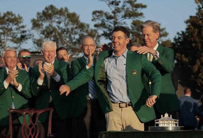 프레드 리들리 오거스타 내셔널 골프클럽 회장(오른쪽)이 마스터스 타이틀 방어에 성공한 로리 매킬로이에게 그린재킷을 입혀주고 있다. (사진=AFPBBNews)