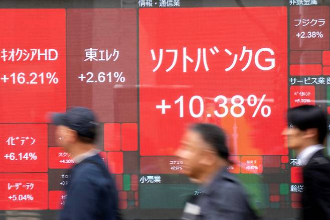 14일 일본 도쿄에서 시민들이 도쿄 증시 주가를 보여주는 전광판 앞을 지나가고 있다. (사진=AFP)