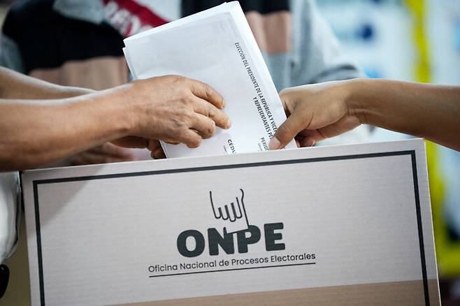 13일(현지시각) 페루 수도 리마에서 투표소 설치 지연과 유권자 접수 인력 부족으로 일부 지역 투표가 이틀째로 이어진 가운데, 선거관리 요원이 한 유권자의 투표를 돕고 있다. 로이터 연합뉴스