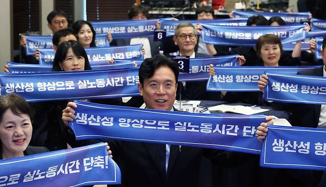 김영훈 고용노동부 장관이 6일 오후 서울 중구 R.ENA컨벤션센터에서 열린 생산성 향상 지원단 발대식에서 참석자들과 '생산성 향상으로 실노동시간 단축' 문구가 적힌 손피켓을 들고 기념촬영을 하고 있다. 뉴스1