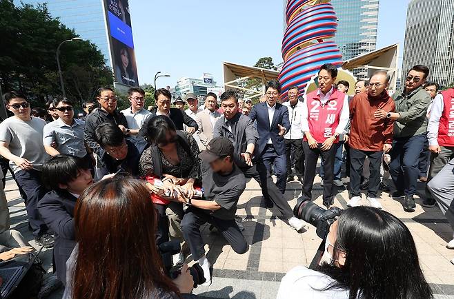 오세훈 국민의힘 서울시장 후보가 15일 서울 청계광장에서 이명박 전 대통령과 환담을 나누던 중 한 남성이 “용산참사 책임자”라고 외치며 이 전 대통령 쪽으로 뛰어들자 경호원들이 제압하고 있다. 뉴스1
