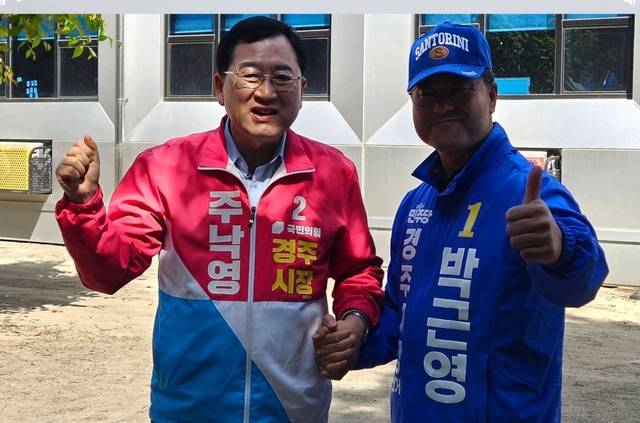 등록을 마치고 본격적인 선거운동에 나선 주낙영 국민의힘 경주시장 후보(왼쪽)와 박근영 후보가 현장에서 만나 손을 잡고 공정경쟁을 다짐하고 있다. 민주당 제공