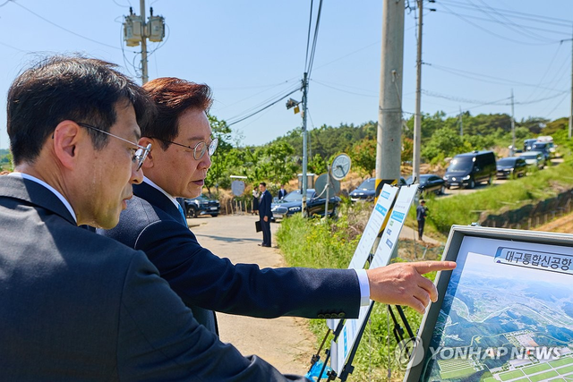이재명 대통령이 지난 15일 대구 군위군과 경북 의성군에 건설될 대구경북통합신공항 예정부지를 방문해 대구시 관계자의 설명을 듣고 있다. 연합뉴스