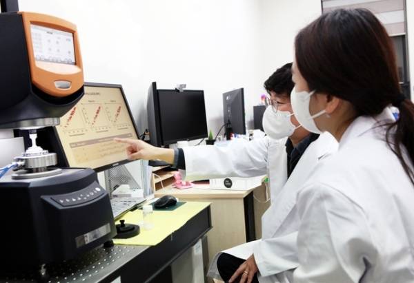 코스맥스 CAI연구소 관계자(앞쪽)와 박준동 숙명여대 화공생명공학부 교수가 AI로 분석한 제형에 대해 상의하고 있다./사진=코스맥스 제공