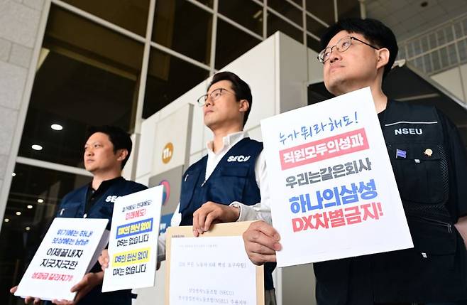 "DX부문 차별말라" 삼성전자의 2·3 노조인 전국삼성전자노동조합 및 동행노조 조합원들이 18일 삼성전자 노사 간 사후조정 절차가 진행된 정부세종청사 고용노동부 입구에서 교섭을 주도하는 최승호 삼성그룹 초기업노조 삼성전자지부 위원장을 향해 DX부문 직원들의 목소리를 반영해달라고 요구하고 있다. 뉴스1