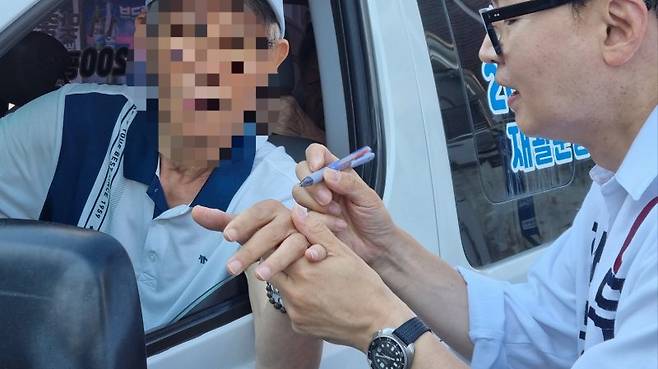 한 주민이 19일 한동훈 후보에게 손바닥에 싸인을 해달라고 요청하자, 한 후보가 이에 응했다. 사진=이해람 기자
