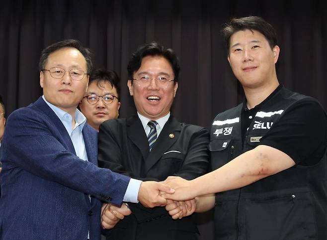 20일 경기 수원시 장안구 경기고용노동청에서 열린 삼성전자 임금협상을 마친 후 여명구 삼성전자 DS(디바이스솔루션·반도체 사업 담당) 피플팀장(왼쪽부터)과 김영훈 고용노동부 장관, 최승호 삼성그룹 초기업노동조합 삼성전자지부 위원장이 잠정 합의한에 서명한 후 손을 맞잡고 파이팅을 외치고 있다. 뉴시스